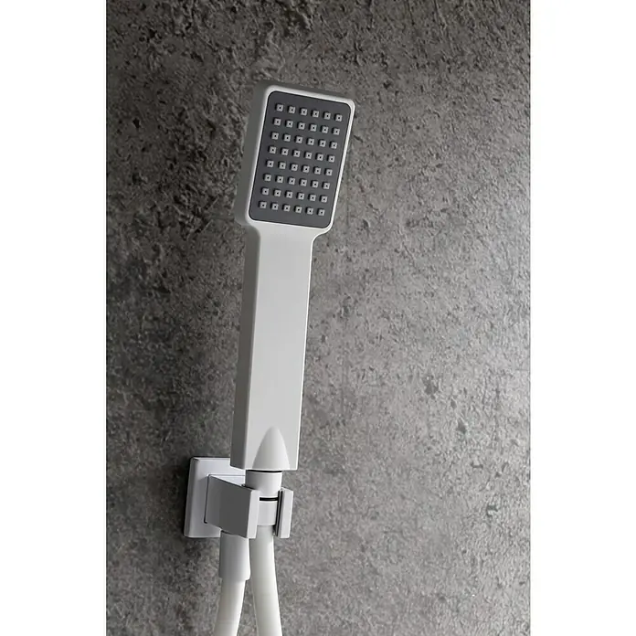 Imex Sistema de ducha empotrado Dublín - Con grifo monomando, Blanco - Primer plano de un moderno cabezal de ducha cuadrado con mango blanco y cara de ducha gris, sobre una pared gris texturizada.