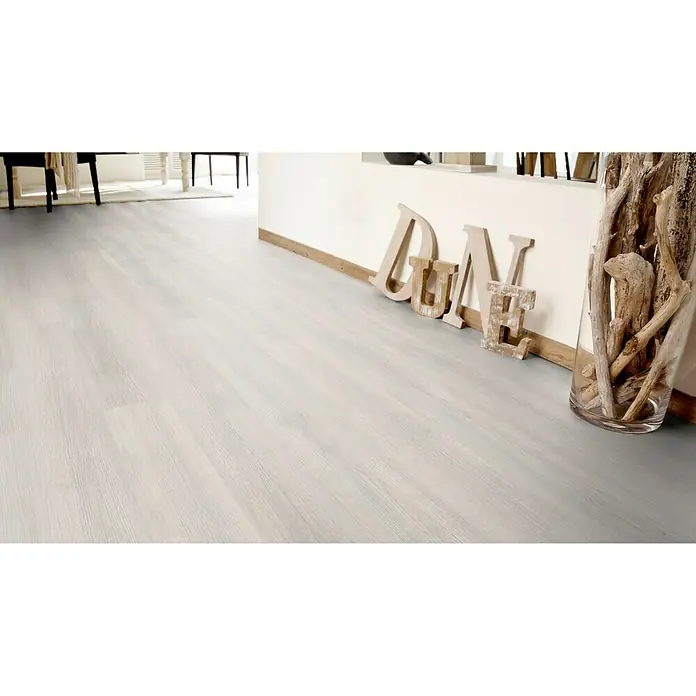 Rodapié Scandinave Wood Beige/Iceberg Pinie - 2,2 m x 13 mm x 90 mm - Primer plano de un suelo de madera de color claro con la palabra "DUNE" y un recipiente de vidrio lleno de madera flotante.