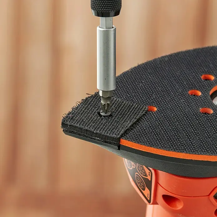 Black+Decker Lijadora multifunción eléctrica  BEW200-QS - 200 W, Número de oscilaciones marcha en vacío: 12.000 r.p.m., Diámetro circuito oscilante: 2 mm - Primer plano de un destornillador apretando un tornillo en el papel de lija negro de una herramienta eléctrica BLACK+DECKER.