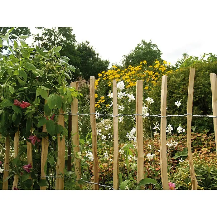 Kiehnholz Staketenzaun - 500 x 90 cm, Haselnuss - Ein naturnaher Holzzaun mit Maschendraht, umgeben von blühenden Pflanzen in einem üppigen Garten. Ideal für naturnahe Gärten.