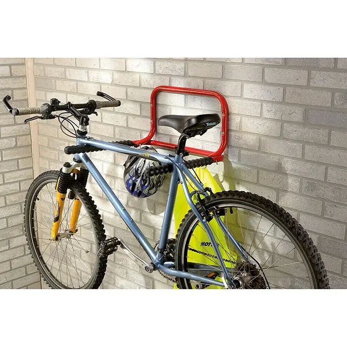 Aparcamiento de bicicletas B053QRA - Acero - Bicicleta sujeta a un portabicicletas rojo en una pared. El portabicicletas sujeta la bicicleta de forma segura y ahorra espacio.