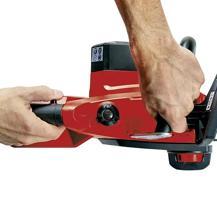 Einhell PXC 18V Motosierra de batería GE-LC 18 Li-Solo - 18 V, Sin batería, Longitud de la cuchilla: 25 cm - Manos operando una motosierra inalámbrica roja. Ideal para trabajos de jardinería y poda de árboles. Libertad sin cable.