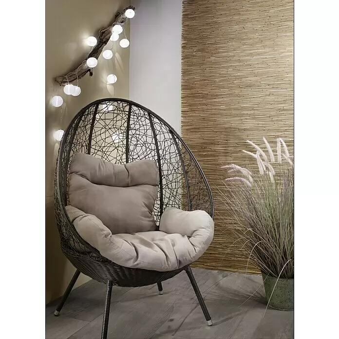 Paulmann Guirnalda luminosa LED Lampion - 3,6 m, Para exterior - Un sillón de huevo de mimbre oscuro con cojines suaves y claros, que crea un rincón acogedor y relajante.
