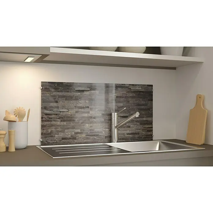CUCINE Küchenrückwand - Stonehenge, 80 x 40 cm, Stärke: 6 mm, Einscheibensicherheitsglas (ESG) - Nahaufnahme einer modernen Küchenspüle mit Wasserhahn, Arbeitsplatte und hölzernen Küchenutensilien vor einer stilvollen Steinwand.