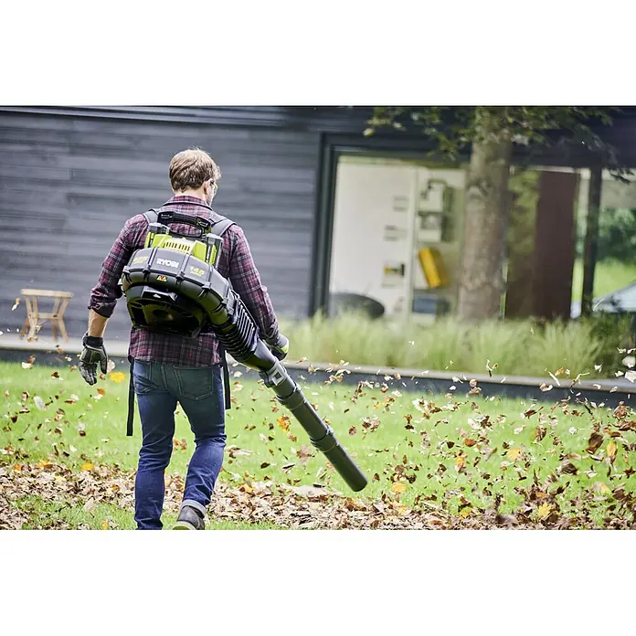 Ryobi Akku-Laubbläser RY36BPXA-0 - 36 V, Ohne Akku, Blasgeschwindigkeit: 0 km/h, Blasleistung: 17,7 m³/min - Ein Mann mit einem Ryobi Akku-Rucksack Laubbläser in Aktion, der Blätter im Garten wegpustet.\n