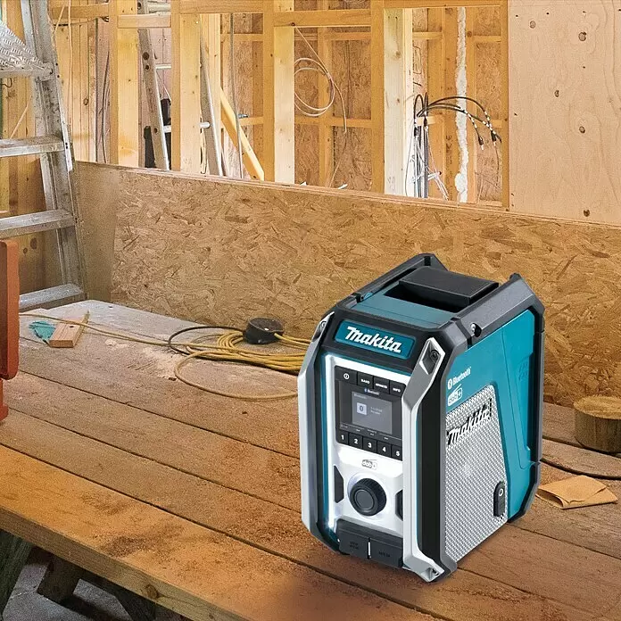 Makita LXT 18V Radio de batería para la obra DMR115 - 18 V, Sin batería, Frecuencia: 174.928 - 239.200 MHz (DAB/DAB+) - Una radio de obra Makita azul y negra con pantalla digital y botones sobre una mesa de madera en un entorno de construcción.