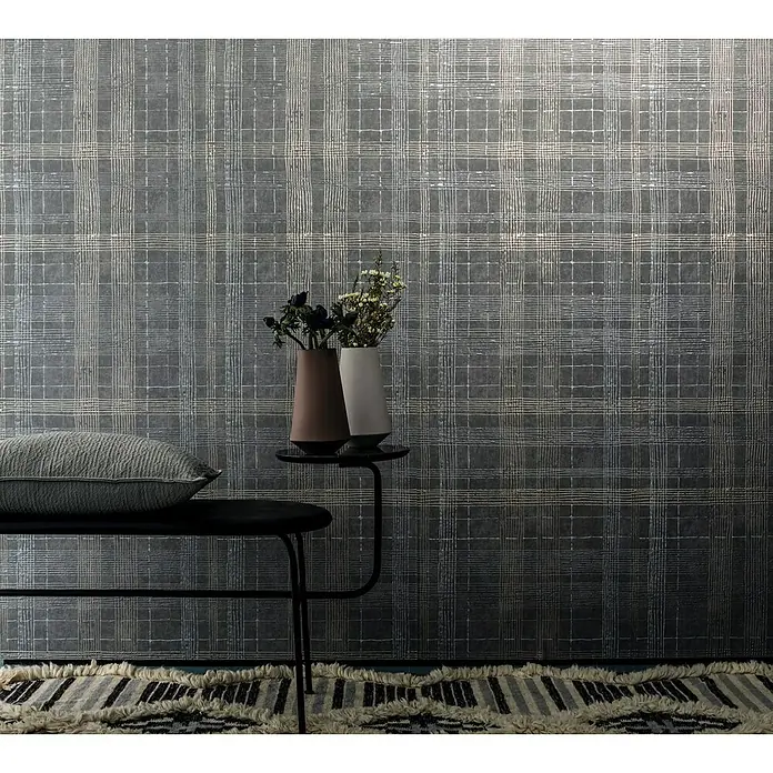 Marburg Casual Vliestapete Karrierte Linien - Grau, Streifen, 10,05 x 0,53 m - Das Bild zeigt eine graue Wand mit einem karierten Muster, einem Kissen auf einer Bank und zwei Vasen auf einem Tisch.