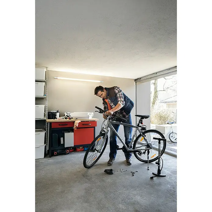 Osram LED Leuchtstoffröhre T8Länge: 60,3 cm, Tageslichtweiß, 8 W, 900 lm, G13 - Ein Mann repariert sein Fahrrad in der Garage. Das Fahrrad steht auf einem Montageständer. Werkzeug liegt herum.