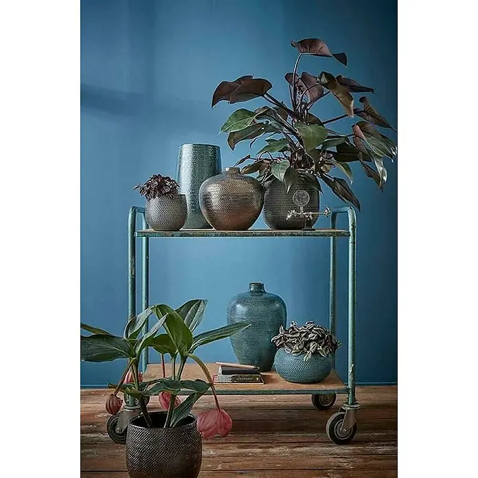 Mica Decorations Übertopf rund Gabriel - Außenmaß (Ø x H): 21 x 19 cm, Bordeaux, Keramik - Dekorative Zimmerpflanzen in stilvollen Töpfen auf einem eleganten Servierwagen vor blauem Hintergrund.
