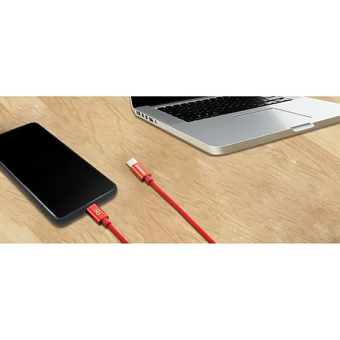 BAUHAUS Cable de carga USB - Rojo, 1 m, Enchufe C a enchufe C - Cable de carga rojo conecta un teléfono inteligente a un ordenador portátil sobre una mesa de madera, ideal para cargar y sincronizar dispositivos.