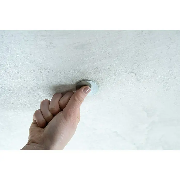 Mini-Rauchmelder-Befestigung - Durchmesser: 4 cm, Kleben - Hand drückt runden magnetischen Deckenhaken an eine Decke mit gemusterter Oberfläche.