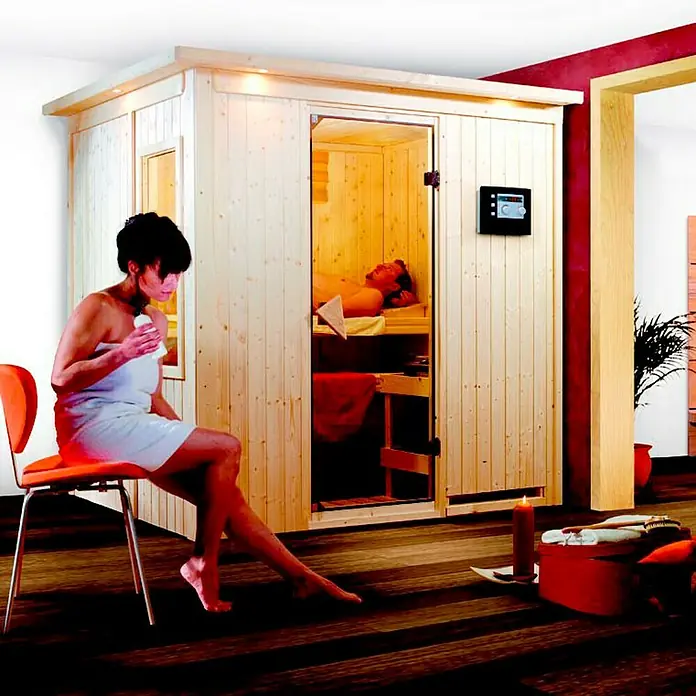 Karibu Elementsauna Fanja - Ohne Ofen, Mit Dachkranz und Beleuchtung, L x B x H: 210 x 165 x 192 cm - Saunabereich mit einer Frau auf einem Stuhl und einem Mann in der Sauna. Entspannung pur mit dieser modernen Sauna!