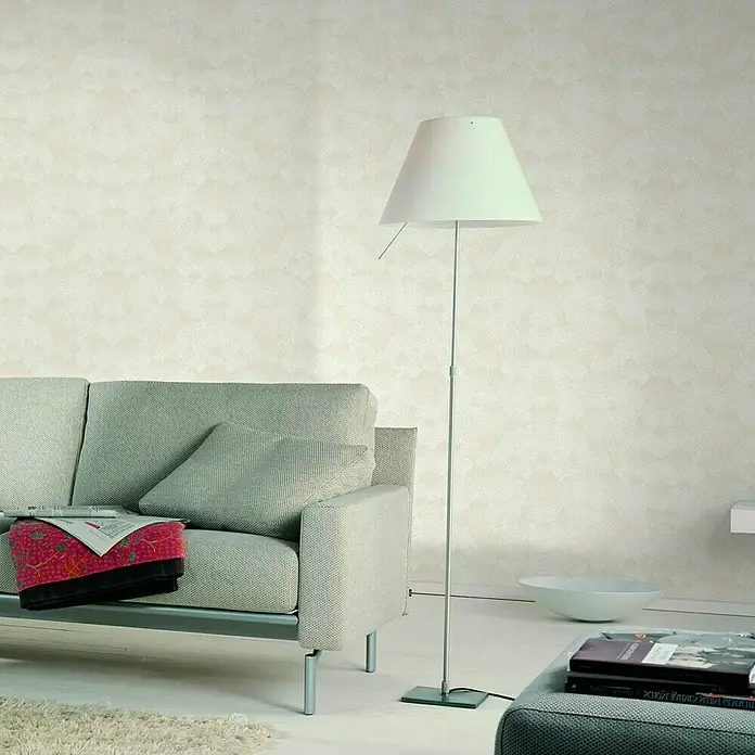 Glööckler Vliestapete - Beige, Grafisch, 10,05 x 0,7 m - Ein modernes Wohnzimmer mit einem grauen Sofa, einer Stehlampe und dekorativer Tapete. Die Lampe ist ein zentraler Fokus.