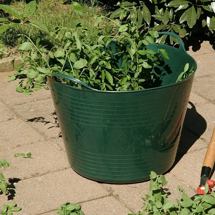 Gartenkorb - Kunststoff, Fassungsvermögen: 40 l, Grün - Ein grüner Flexibler Eimer, gefüllt mit abgeschnittenen Ästen und Blättern, steht auf einem gepflasterten Bereich im Garten.