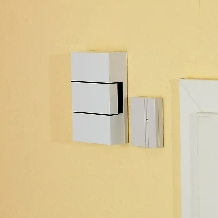 Heidemann Funkkonverter HX - Batteriebetrieben, Reichweite ca.: 100 m, Geeignet für: Alle HX-Geräte - Nahaufnahme einer modernen weißen Türklingel und einer Gegensprechanlage an einer gelben Wand neben einem weißen Türrahmen.