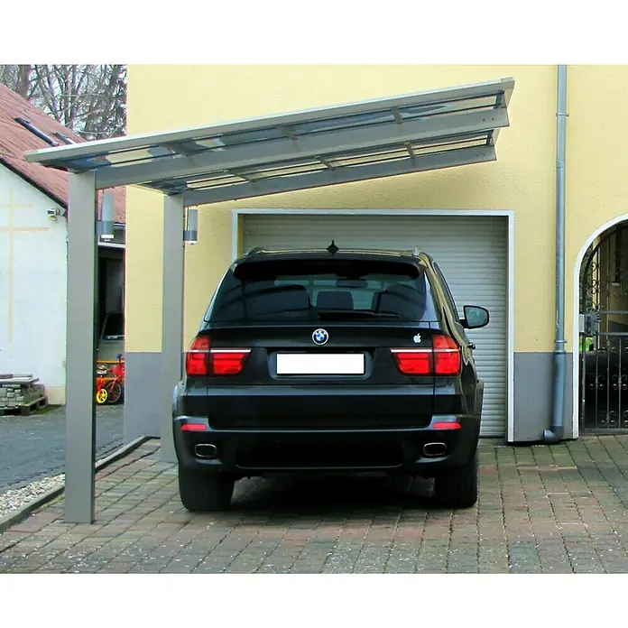 Ximax Carport LINEA 80 - Außenmaß inkl. Dachüberstand (B x T): 2,73 x 4,95 m, Einzelcarport, Edelstahloptik - Das Bild zeigt ein Carport mit einem schwarzen Auto darunter, das vor einer Garage geparkt ist. Es bietet Schutz vor Wettereinflüssen.