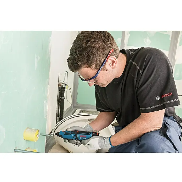 Bosch Professional Akku-Multifunktionswerkzeug GRO 12V-35 - 12 V, Leerlaufdrehzahl: 5.000 U/min - 35.000 U/min - Ein Mann arbeitet mit einem Bosch Professional Multifunktionswerkzeug im Badezimmer, um ein Rohr zu bearbeiten.
