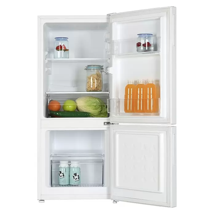 PKM Kühl-Gefrierkombination KG117EW - Nutzinhalt Gesamt: 117 l, 49,5 x 47 x 114 cm, Weiß - Offener weißer Zweitürer-Kühlschrank mit frischen Lebensmitteln: Gläser mit Obst, Trockenpilze, Orangensaftflaschen, Gemüse und Milchgetränken.