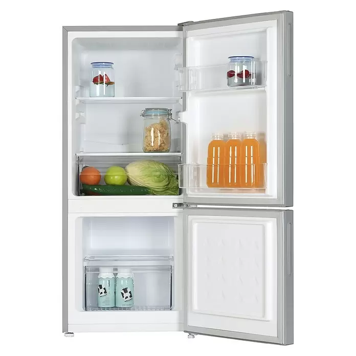 PKM Kühl-Gefrierkombination KG117ES - Nutzinhalt Gesamt: 117 l, 49,5 x 47 x 114 cm, Silber - Geöffneter silberner zweitüriger Kühlschrank, der Lebensmittel im Kühl- und Milch im Gefrierfach zeigt.