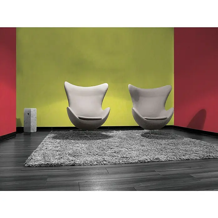 A.S. Création Vliestapete - Grün, Uni, 10,05 x 0,53 m - Zwei moderne, graue Sessel auf einem flauschigen Teppich vor einer farbenfrohen Wand. Ideal für stilvolle Wohnräume und Lounges.
