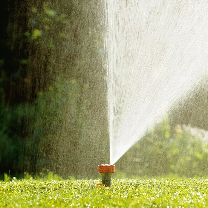Gardena Classic Regner 4-Flächen-Regner TWIST - Max. Regnerfläche: 100 m², Anzahl Sprühformen: 4 Stk., Erdspieß - Rasensprenger in Aktion: Bewässerung mit einem Regner, der das Gras mit Wasser besprüht, um es grün und gesund zu halten.