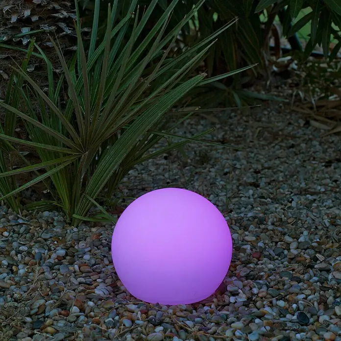 New Garden Design-Außenleuchte Buly 20 - Durchmesser: 20 cm, E27, IP65 - Leuchtende, pinkfarbene Kugel auf Kies vor Pflanzen. Perfekt für stimmungsvolle Gartenbeleuchtung und als dekoratives Element im Außenbereich.