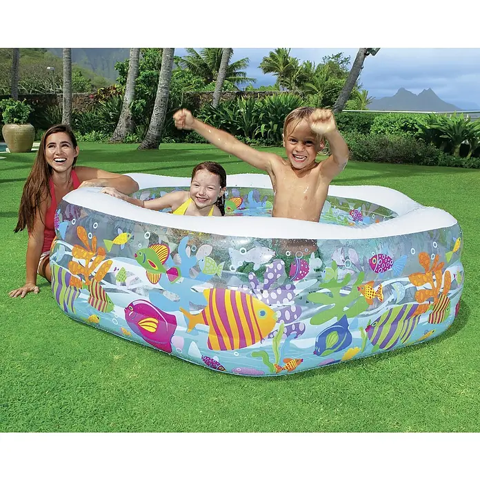 Intex Ozean Reef Piscina hinchable - 191 x 178 x 61 cm - Una piscina inflable con un tema submarino donde los niños están jugando, mientras una mujer está sentada y mirando.