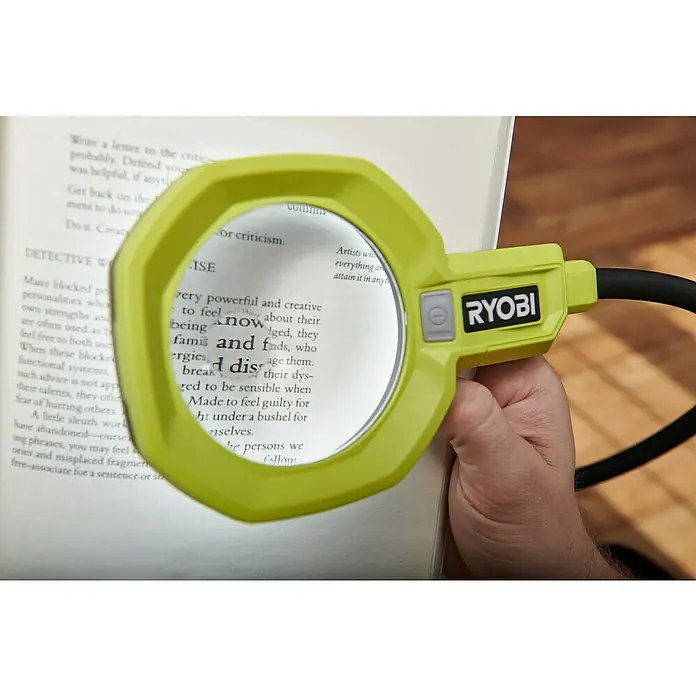 Ryobi ONE+ Akku-Lupenleuchte RML18-0 - 18 V, Ohne Akku - Nahaufnahme einer gelben RYOBI Leselupe, die ein Buch vergrößert, ideal für detailorientiertes Arbeiten oder Lesen.