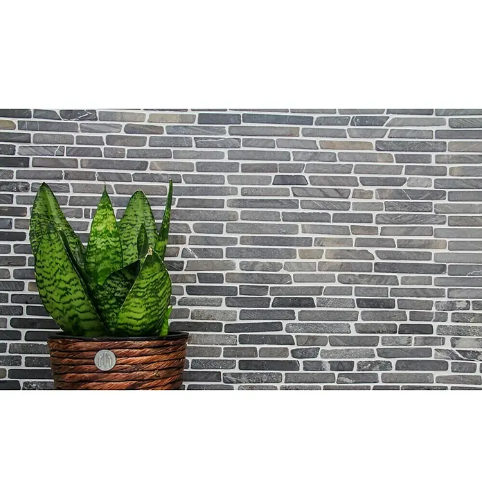 Mosaikfliese MOS BRICK 125 - 30,5 x 30,5 cm, Schwarz, Matt - Eine Nahaufnahme einer Pflanze in einem Korb vor einer grauen Ziegelwand, die eine friedliche Atmosphäre erzeugt.