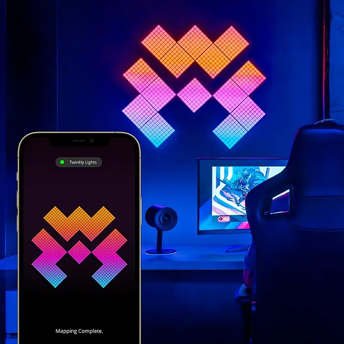 Twinkly LED-Panel-Set Squares RGB StartersetRGB - Twinkly Lights Paneele in einem Gaming-Setup, gesteuert per Smartphone-App, die leuchtende Farben für eine stimmungsvolle Atmosphäre erzeugen.