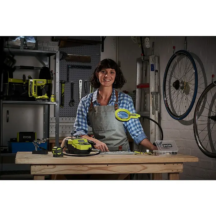 Ryobi ONE+ Akku-Lupenleuchte RML18-0 - 18 V, Ohne Akku - Eine Frau arbeitet mit einem Ryobi-Drehwerkzeug und einer Inspektionsleuchte an einem Holztisch in ihrer Werkstatt.