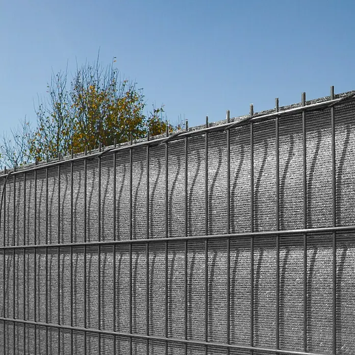 Peddy Shield Sichtschutz - HDPE Gewebe, Anthrazit, 5 x 1,4 m - Ein grauer Doppelstabmattenzaun mit Sichtschutz vor blauem Himmel.