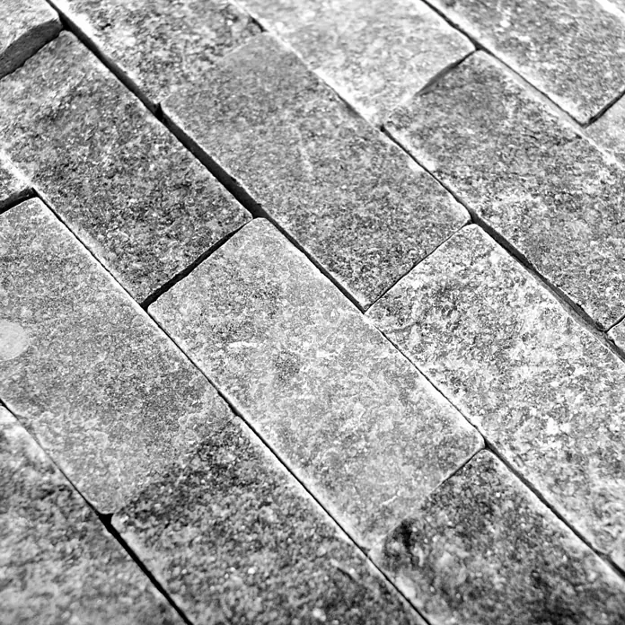 Mosaikfliese Brick Splitface X3D 48196 - 30,5 x 29 cm, Anthrazit, Matt - Nahaufnahme von grauen rechteckigen Ziegeln. Die Oberfläche ist rau und uneben, was dem Material eine natürliche und robuste Note verleiht.