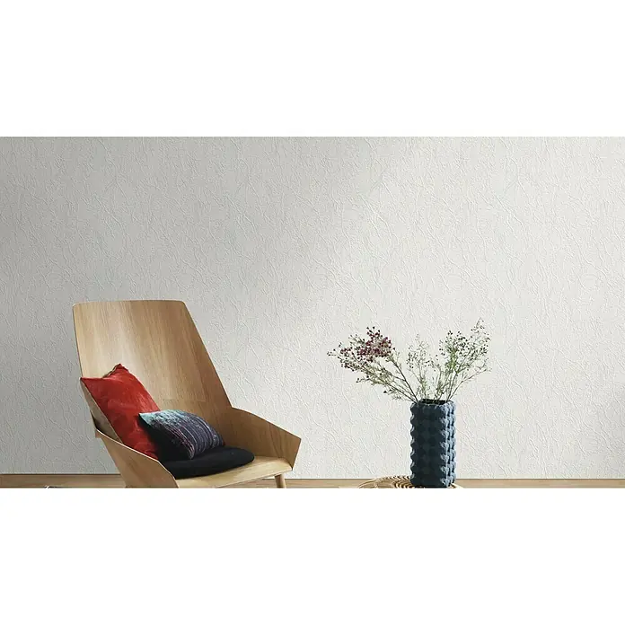 Rasch Vliestapete Putzstruktur II - Weiß, Uni, 10,05 x 0,53 m - Ein stilvoller Raum mit einem Sessel mit Kissen und einer eleganten Vase mit floralen Akzenten vor einer strukturierten Tapete.