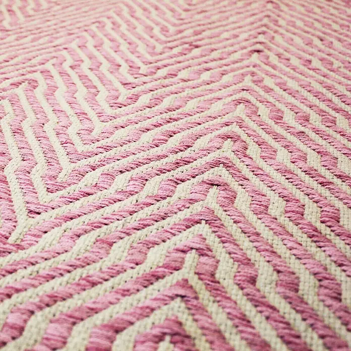 Kayoom Flachgewebeteppich Cocktail 400 - Pink, 230 x 160 cm, 100% Baumwolle - Nahaufnahme eines rosa-beigen Teppichs mit geometrischem Zickzackmuster, der Textur und Design hervorhebt.