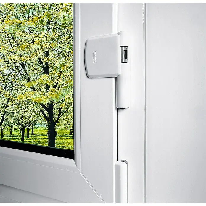 Abus Scharnierseitensicherung FAS101 - Weiß - Weißer ABUS-Fenstergriff sorgt für erhöhte Sicherheit. Zu sehen ist die verriegelte Position vor einem Fenster mit Blick auf blühende Bäume.