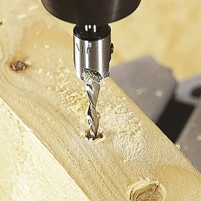 Wolfcraft Broca para madera - 2 ud., Diámetro de la broca: 16 mm - Una broca de metal plateado con avellanador integrado perfora un agujero guía en una tabla de madera clara.