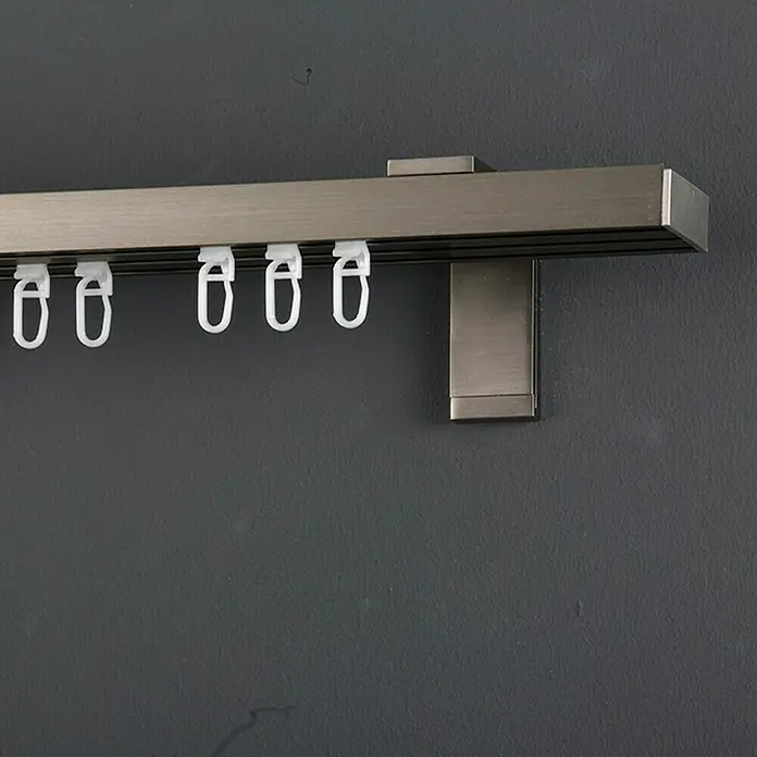 Expo Ambiente Gardinenprofil Smart Set - Anzahl Läufe: 3 Stk., Silber, 160 cm - Nahaufnahme einer Gardinenschiene in gebürstetem Metall mit weißen Gleitern zur Befestigung von Vorhängen an einer grauen Wand.