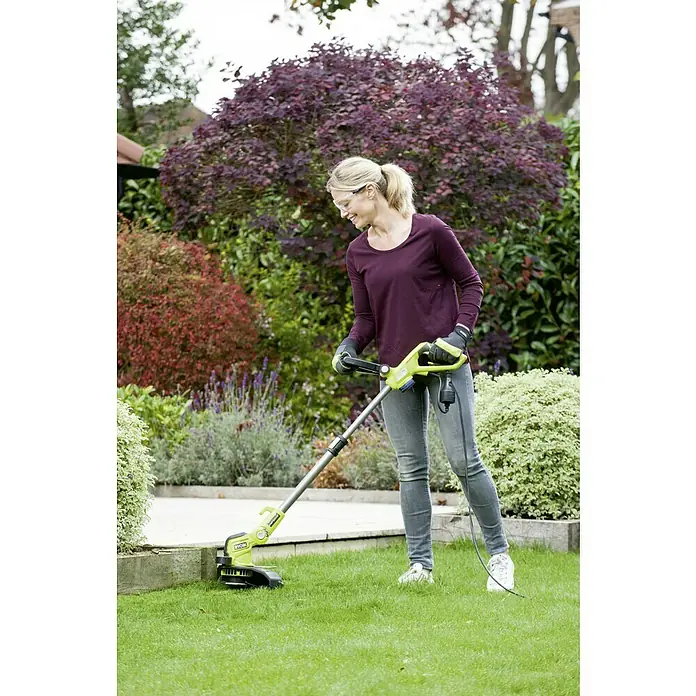 Ryobi Elektro-Rasentrimmer RLT6130 - 600 W, Schnittbreite Faden: 30 cm - Eine Frau benutzt einen Ryobi Rasentrimmer im Garten, um präzise Rasenkanten zu schneiden. Das Gerät ist in Grün und Schwarz gehalten.