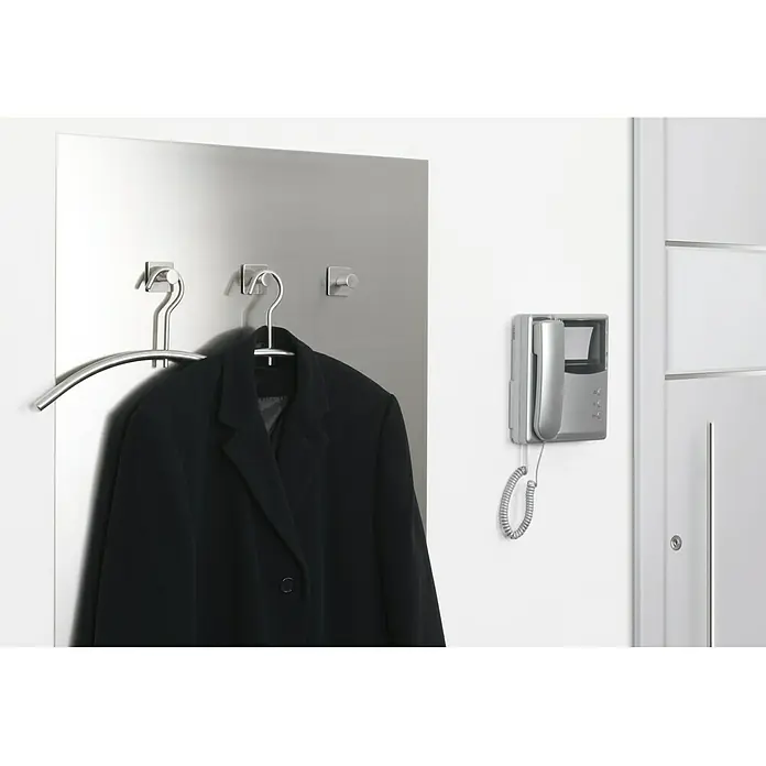 Tesa Cinta adhesiva de papel Powerbond Ultra Fuerte - 5 m x 19 mm - Un perchero plateado con una chaqueta negra y un intercomunicador cuelgan en la pared. Elegante conjunto de perchero.
