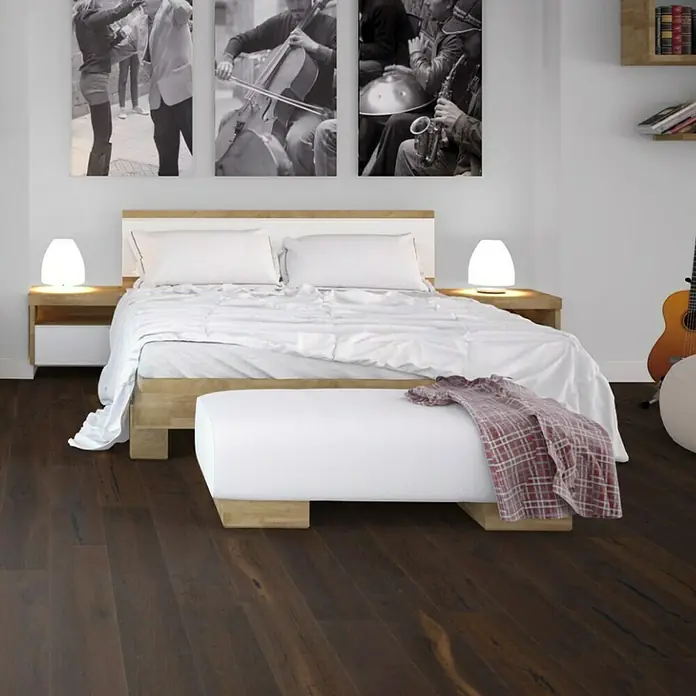 Parkett - Eiche Grindelwald, Landhausdiele, 1.900 x 190 x 15 mm - Das Bild zeigt ein Schlafzimmer mit einem stilvollen Holzbett, weißen Kissen und einer passenden Bank, die das elegante Design unterstreichen.