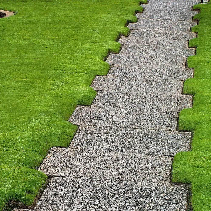 EHL WaschbetonplatteGrau, 40 x 60 x 4 cm - Detailaufnahme eines mit Gras gesäumten Kiesweges, der eine attraktive Gartenlandschaft zeigt.