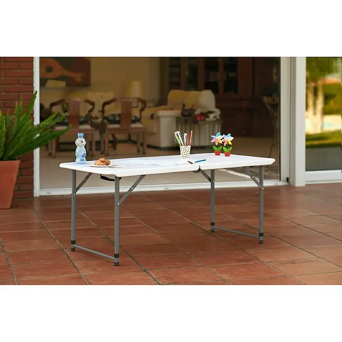 Mesa de jardín Alan - L x An x Al: 122 x 61 x 74 cm, HDPE/Acero, Blanco roto - Imagen de una mesa plegable blanca con estructura gris en el exterior, adornada con papelería, comida y decoraciones.