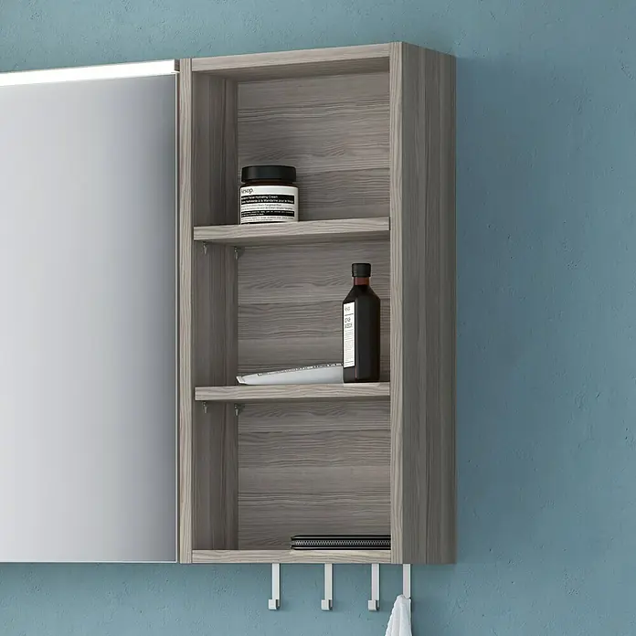 Camargue Cube Regal - 30 x 16 x 62 cm, Eiche Cordoba - Ein grauer Spiegelschrank mit offenen Regalen und verschiedenen Badutensilien vor einer blau gestrichenen Wand.