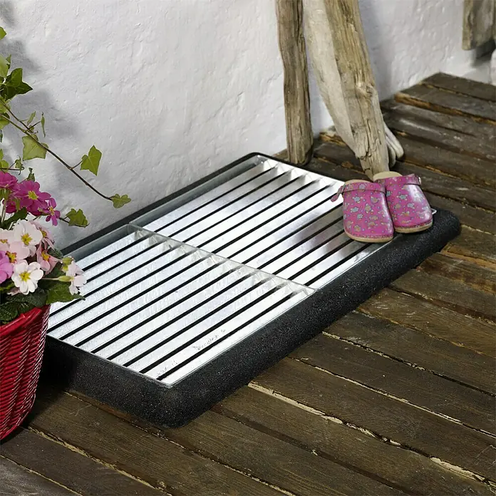 Plus Fußabtreter Cubic - 48 x 88 x 4 cm, Sonstiges - Schmutzfangmatte mit Gitterrosten und Gummirand, daneben ein Korb mit bunten Blumen und ein Paar rosa Kindergartenschuhe.