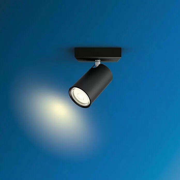 Philips Foco de pared Kosipo - 10 W, L x An x Al: 10,2 x 10,2 x 13,4 cm, Negro, GU10 - Foco negro de techo, ajustable, que ilumina con luz cálida sobre un fondo azul.