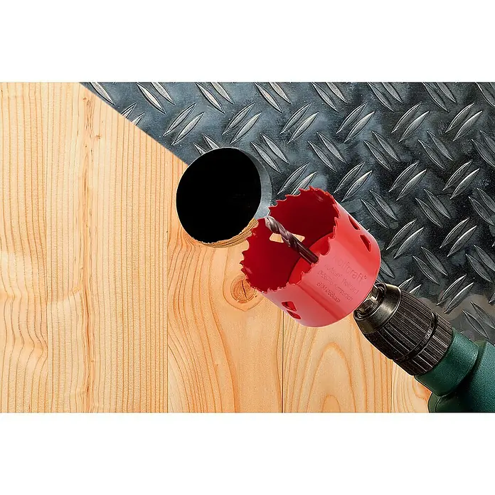 Wolfcraft Lochsäge - Arbeitsdurchmesser: 100 mm, Schnitttiefe: 40 mm - Eine rote Lochsäge von Wolfcraft an einer Bohrmaschine, die ein Loch in ein Holzbrett bohrt, daneben eine Metallplatte.