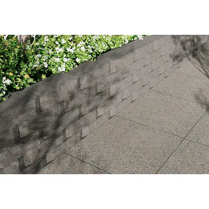 Christoph Mauerstein Antikblock - 30 x 15 x 7,5 cm, Grau, Beton - Bild eines modernen Außenbereichs mit grauen Bodenfliesen und einer stilvollen Mauer mit Pflanzen.
