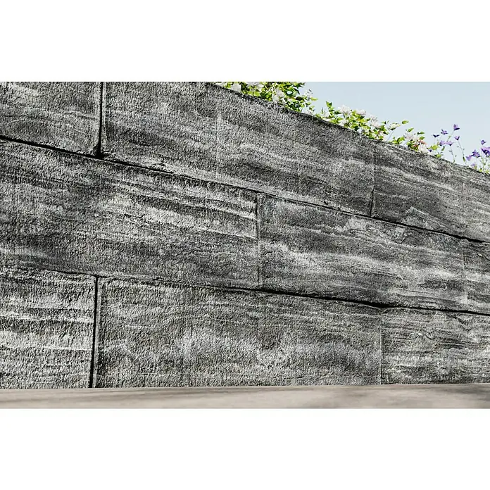 Christoph Mauerstein Rustikalblock - 50 x 12,5 x 14 cm, Anthrazit/Weiß, Beton - Nahaufnahme einer modernen Stützmauer aus grauen Betonsteinen mit horizontaler Maserung und einigen Pflanzen auf der Oberseite.