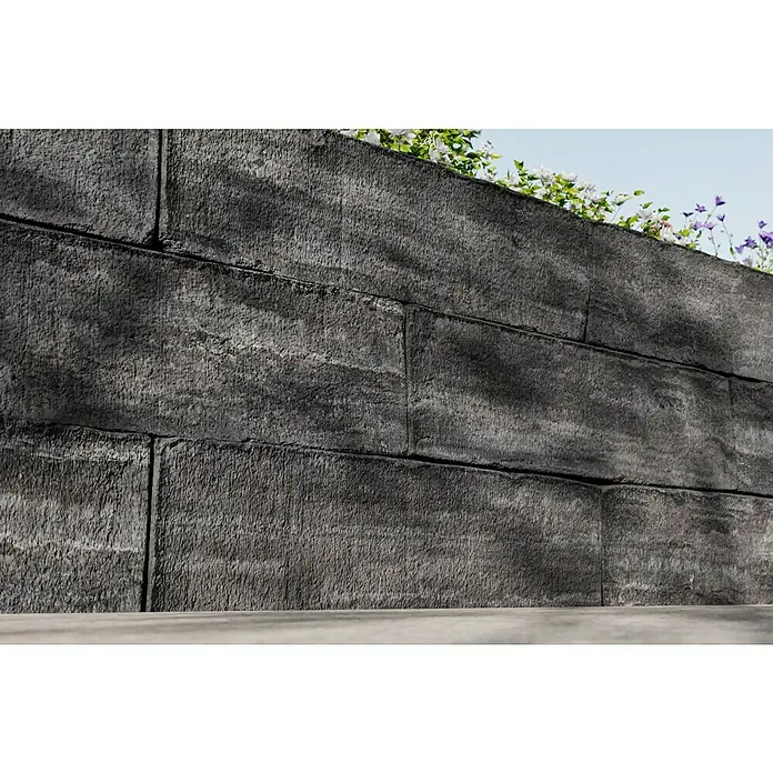 Christoph Mauerstein Rustikalblock - 50 x 12,5 x 14 cm, Kristall/Anthrazit, Beton - Graue Steinmauer mit Pflanzen obenauf, die Textur und Robustheit vereint, während sie als strukturierte Gartenstützmauer dient.
